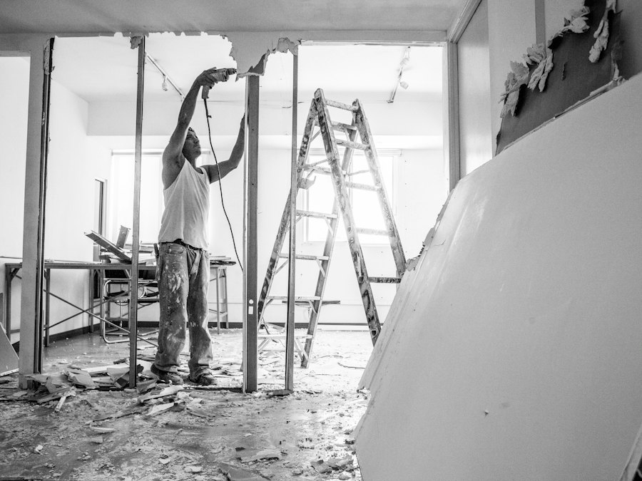 Handwerker auf einer Leiter beim Rückbau einer alten Decke